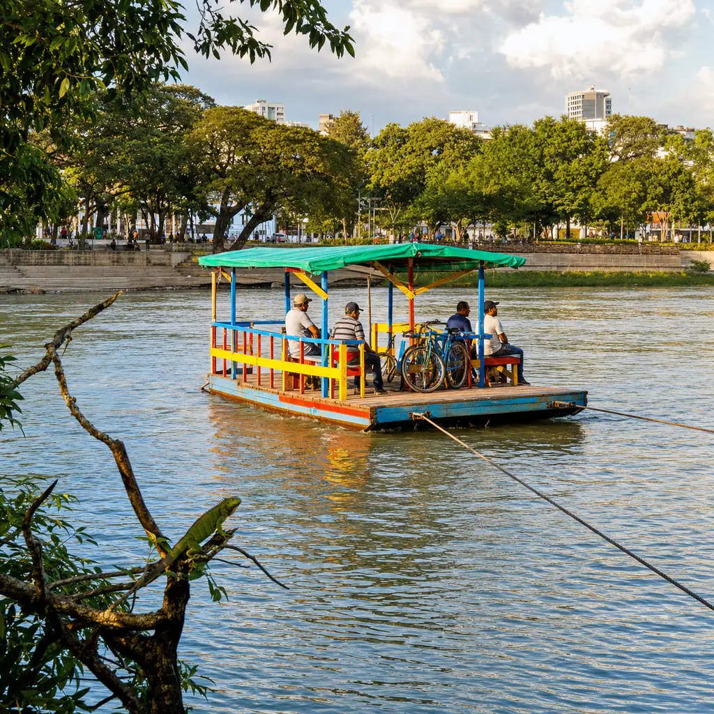 A colorful wooden planchón carrying adult passengers and bicycles across the Sinú River beside Montería's tree-lined waterfront.